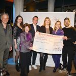 Ein „Spendenscheck“ wird in die Kamera gehalten, mehrere Leute lächeln in die Kamera: Kai Gosslar, Linda Hesse, Steffen Henssler und Thimon von Berlepsch mit Vertreter*innen von Rotaract Hamburg Alstertal und Rotary