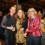 Drei Frauen lächeln oder lachen in die Kamera.