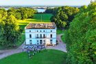 Eine Drohnen-Aufnahme vom Jenisch-Haus, einem prächtigen alten Haus mitten im Park. Es sind viele Bäume des Jenisch-Parks zu erkennen und im Hintergrund die Elbe.