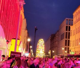 Bunte Lichter und Menschenmenge bei Nacht.
