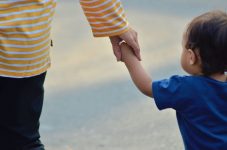 Erwachsene halten das Hand eines Kindes.